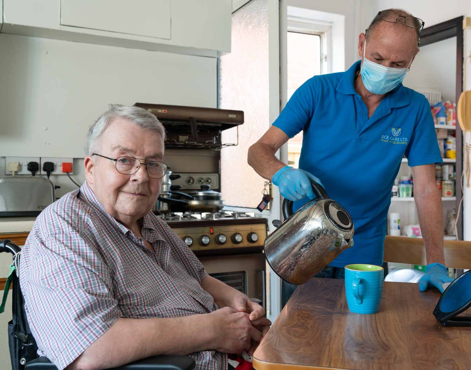 Home carer pouring tea for an older gentleman, photographed for a care provider in Newport