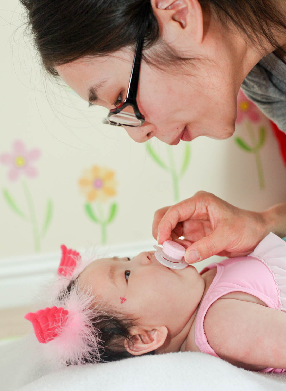 Mother leaning over her baby daughter during a relaxed family photography session at home