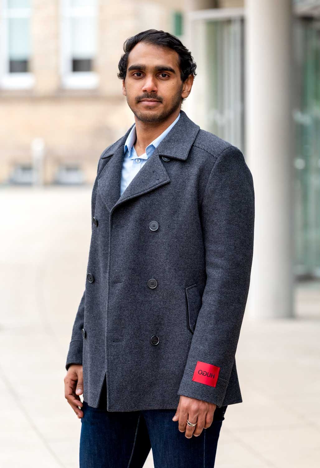 Man in a grey wool coat photographed outdoors for a relaxed individual portrait