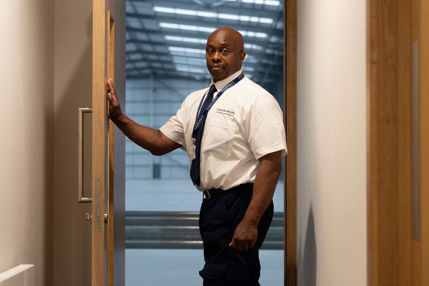 Security officer holding open a door at a distribution centre, commercial photography in Wales
