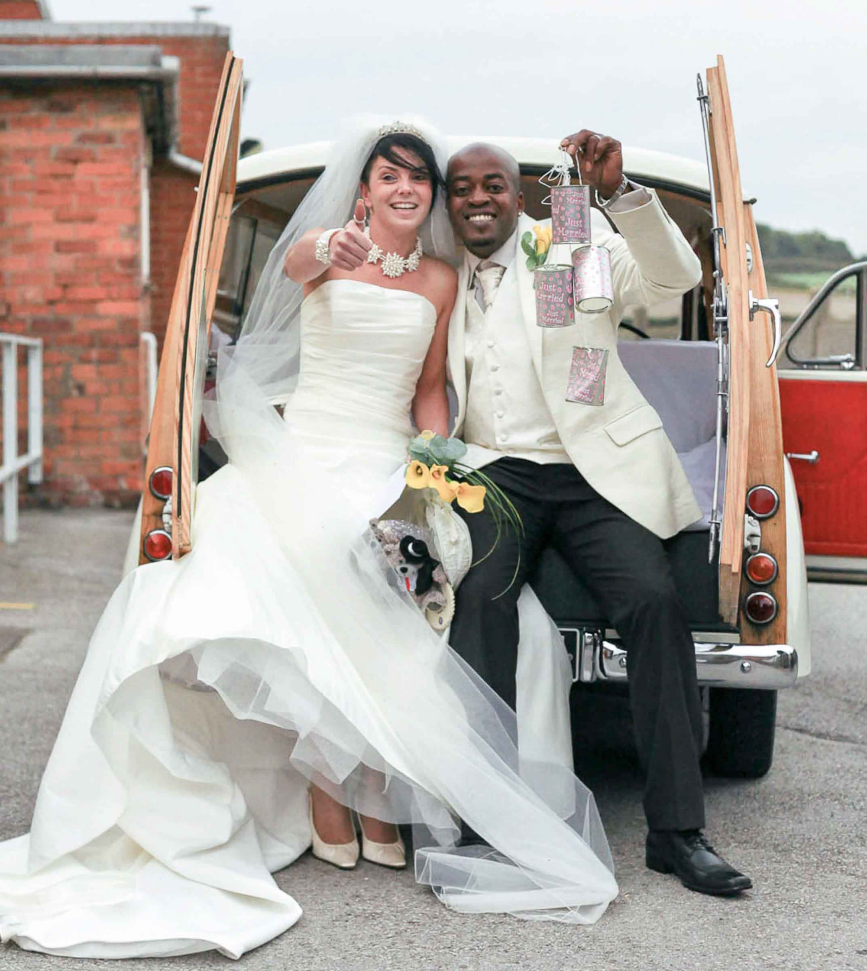 Bride and groom celebrating in a vintage wedding car after their Newport wedding ceremony